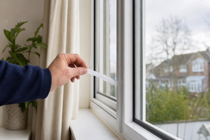 Checking a double glazed window frame for draughts with a tissue strip